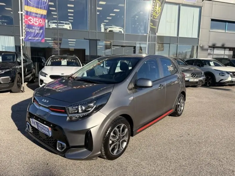 KIA Picanto 2023 gris foncé en 3/4 avant droit, avec détails rouges GT Line sur la calandre et les bas de caisse.