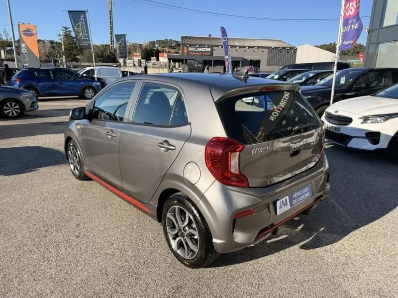 Vue 3/4 arrière droite d'une KIA Picanto GT Line 2023 gris foncé avec jantes sport et détails rouges sur le bas de caisse.
