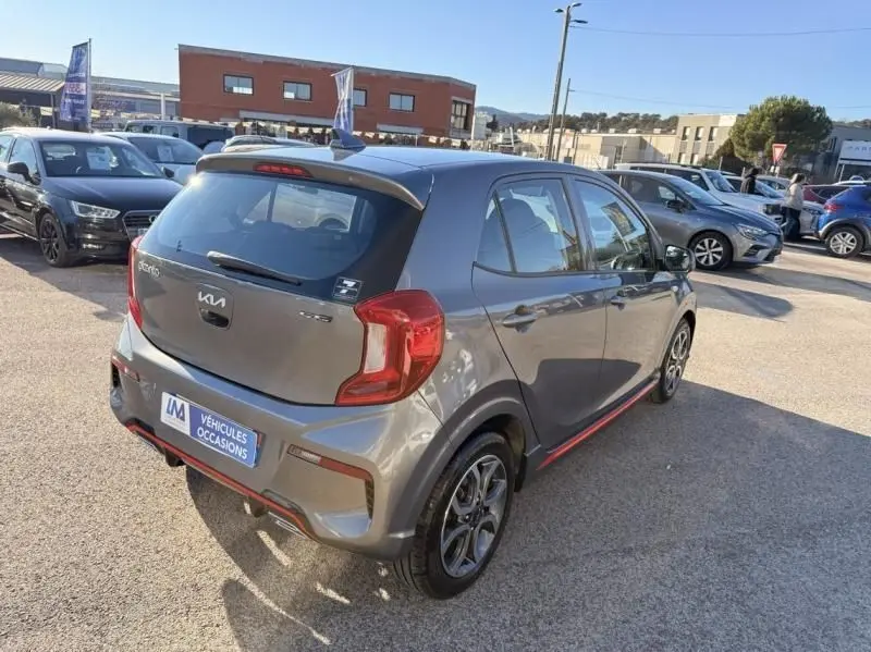 Vue 3/4 arrière droite d'une Kia Picanto GT Line 2023 gris foncé avec détails rouges et jantes alliage distinctives.