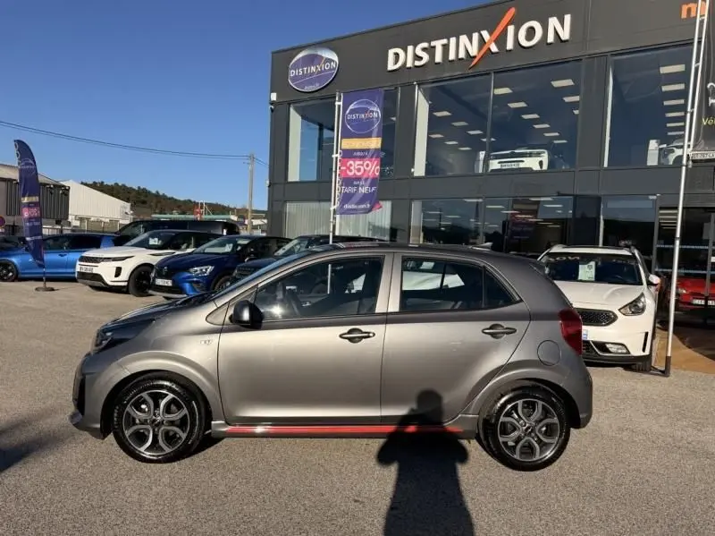 Vue de profil côté gauche d'une KIA Picanto gris foncé 2023 GT Line avec jantes sport et détails rouges au bas de caisse.