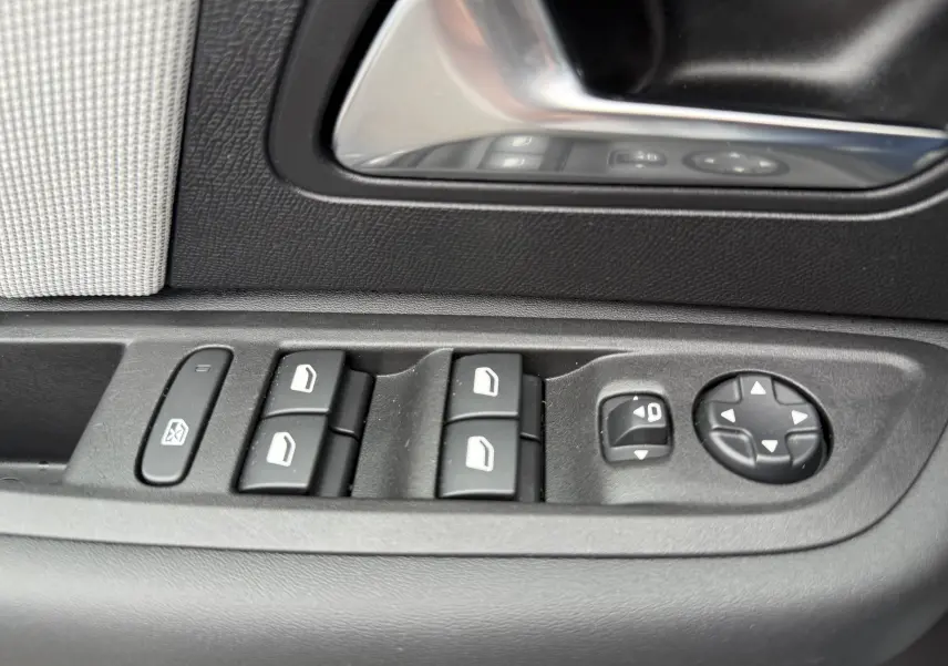 Gros plan sur les commandes de lève-vitres et rétroviseurs côté conducteur d'une Citroën C4 Hybrid 145 blanc Okenite.