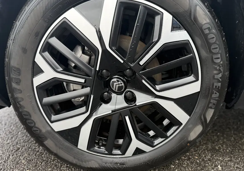 Gros plan sur la jante noire et argentée d’une Citroën C4 Hybrid 145 e-DCS6 Max blanche, pneu Goodyear visible.