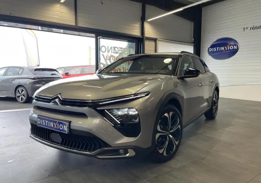 Citroën C5 X gris foncé vue 3/4 avant droit en intérieur, avec calandre distinctive et jantes modernes.