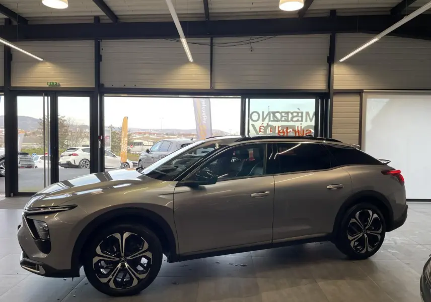 Vue de profil côté gauche d'une Citroën C5 X 2024 gris foncé, soulignant ses jantes noires et son design élancé.