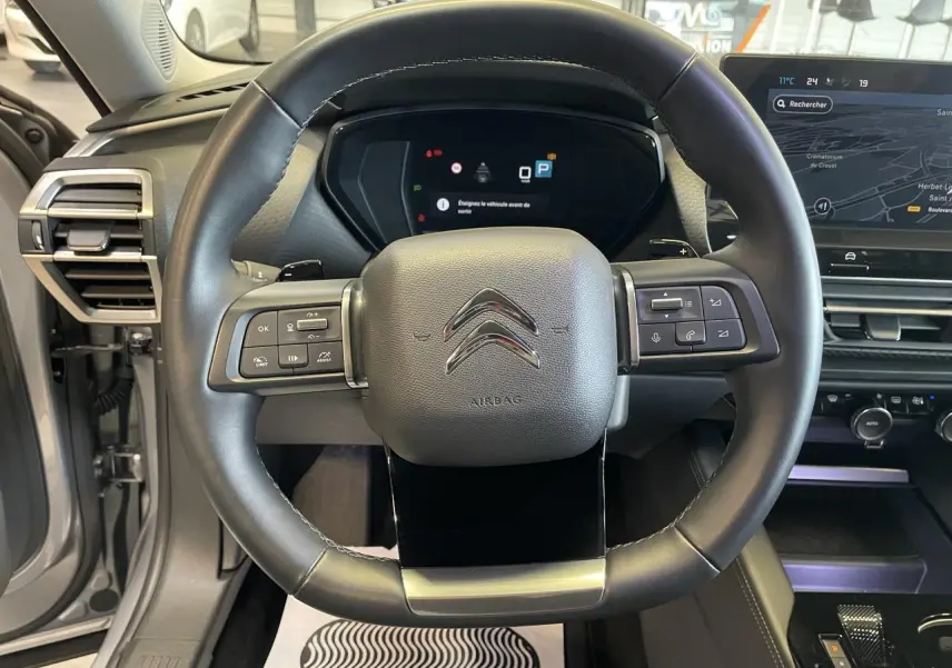 Vue centrée sur le volant cuir noir du Citroën C5 X gris foncé 2024 avec tableau de bord numérique et écran tactile.