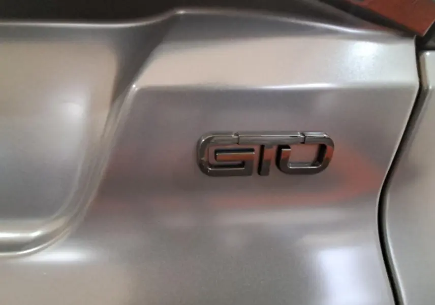 Gros plan sur l’inscription GTO en relief sur la carrosserie gris clair de l’Aixam Ambition 2024.