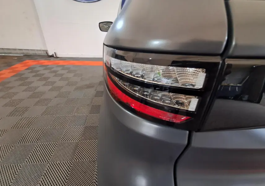 Gros plan sur le feu arrière droit gris clair de l’Aixam Ambition 2024 avec finition GT et jantes noires diamantées visibles.