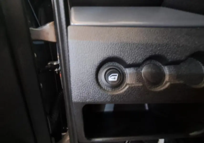 Gros plan sur le bouton d'ouverture du coffre côté conducteur de l'AIXAM AMBITION gris clair 2024.