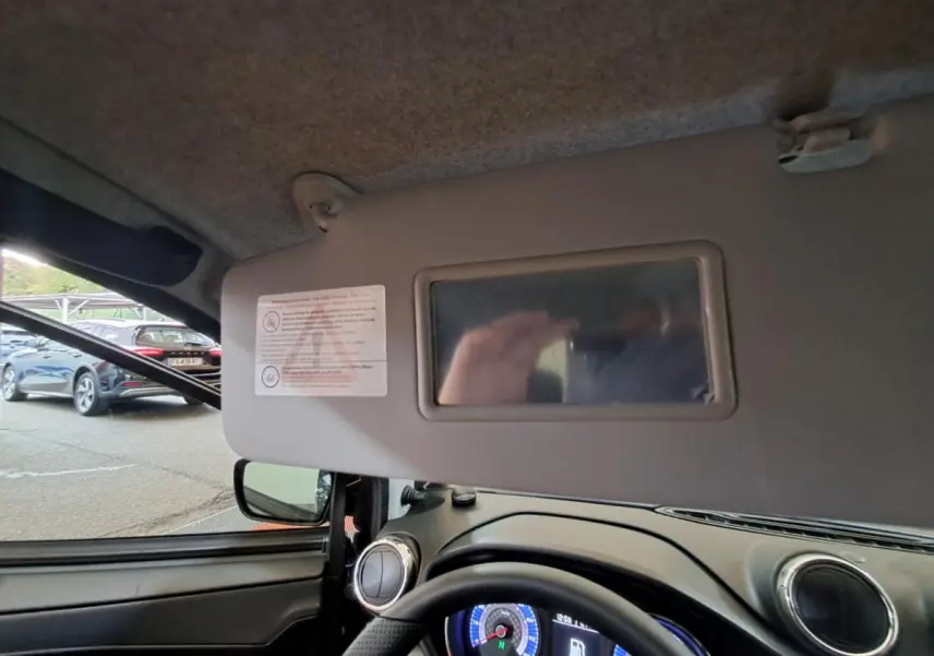 Vue intérieure côté conducteur de l’AIXAM AMBITION gris clair 2024, avec tableau de bord et pare-soleil équipé d’un miroir.