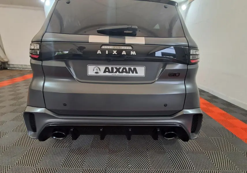 Vue arrière d'une Aixam Ambition gris clair avec logo GTO, double sortie d'échappement et bande décorative blanche sur le toit.