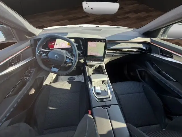 Vue intérieure avant du Renault Austral 2025 hybride, montrant le tableau de bord moderne et les écrans numériques.