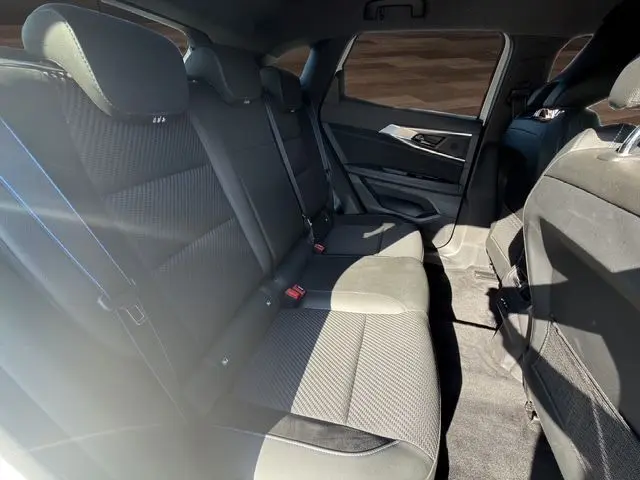 Vue intérieure montrant les sièges arrière en tissu gris foncé du Renault Austral 2025 avec portes ouvertes côté droit.