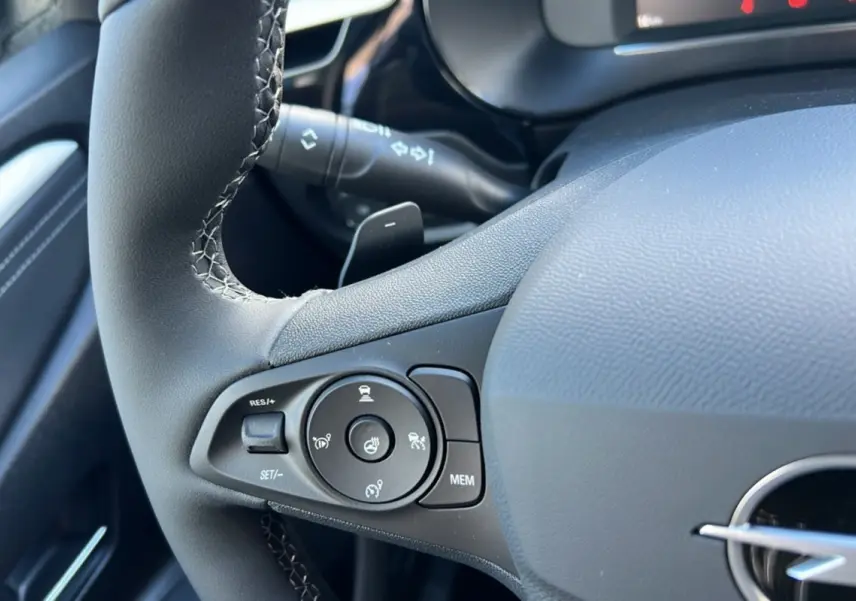Gros plan sur le volant cuir noir de l’Opel Corsa Hybrid 2026, avec commandes multifonctions et bouton de régulateur de vitesse.