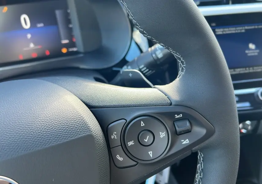 Gros plan sur le volant cuir noir de l’Opel Corsa Hybrid 2026 avec commandes multifonctions et affichage numérique en arrière-plan.