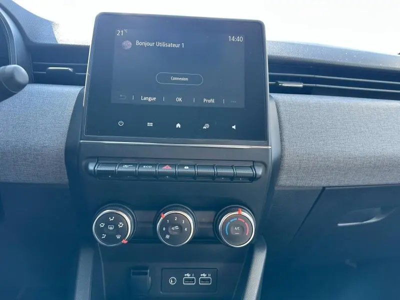 Vue rapprochée de la console centrale de la Renault Clio gris Rafale 2025 avec écran tactile et commandes manuelles de climatisation.