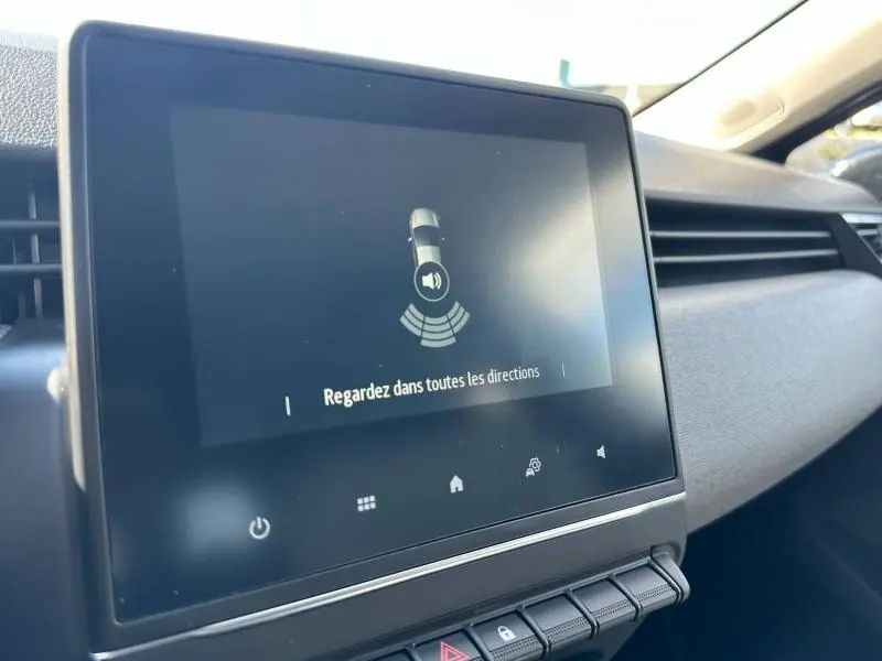 Écran tactile central affichant une alerte de surveillance, intérieur gris clair de la Renault Clio 2025 côté passager.