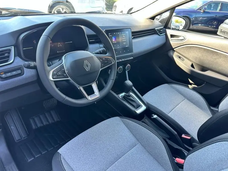 Vue intérieure côté conducteur de la Renault Clio 2025, volant multifonction, écran tactile et sièges gris motif 3D.