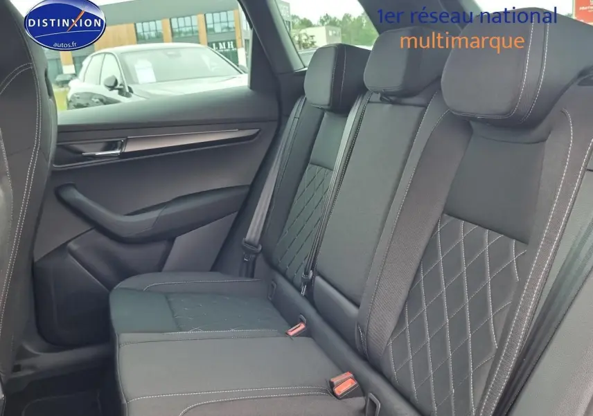 Vue latérale gauche de l'intérieur arrière du Skoda Karoq noir avec sièges tissu à surpiqûres blanches et appuie-têtes.