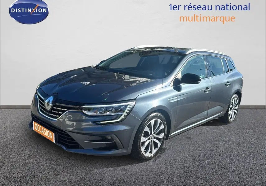 Renault Mégane Break gris titanium métal vue 3/4 avant droit avec jantes bi-ton et feux LED allumés.