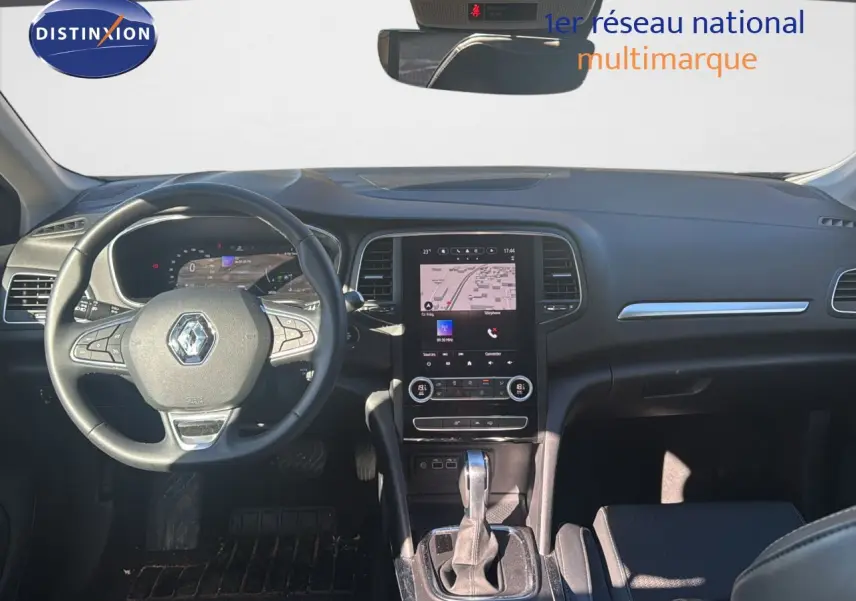 Vue intérieure avant du tableau de bord et volant noir de la Renault Mégane Break 2024 avec écran tactile central et levier de boîte auto.