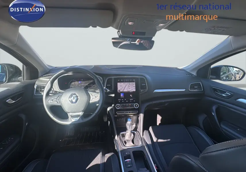 Vue intérieure avant de la Renault Mégane Break 2024, tableau de bord noir avec écran tactile et volant multifonction.