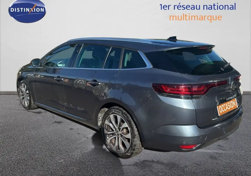 Renault Mégane Break gris titanium métal vue 3/4 arrière droit avec jantes alliage et feux LED allumés.