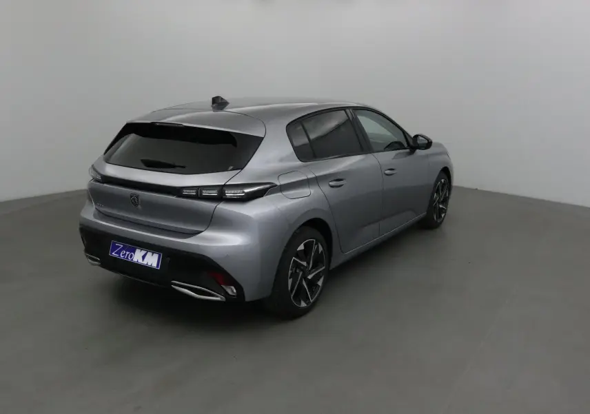Peugeot 308 gris Artense vue 3/4 arrière côté droit dans un studio avec vitres teintées et jantes noires.