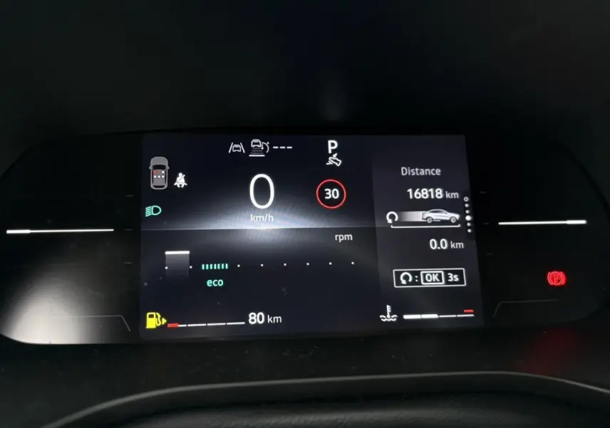 Tableau de bord numérique de Renault Arkana 2025 affichant vitesse, autonomie et alertes, vue frontale rapprochée.