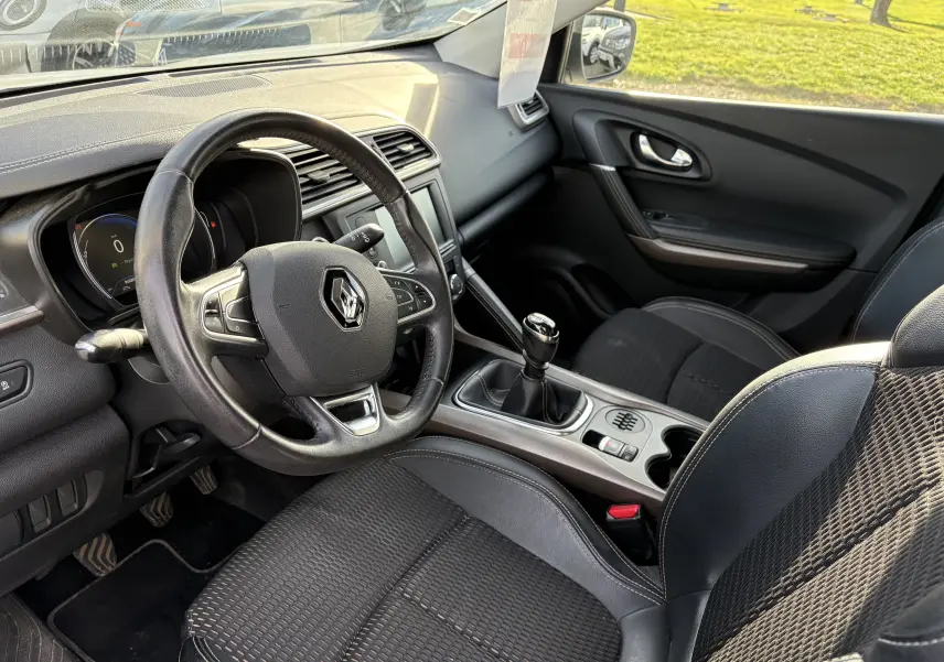 Vue intérieure côté conducteur du Renault Kadjar blanc 2015, mettant en valeur le volant, la boîte manuelle et la console centrale.
