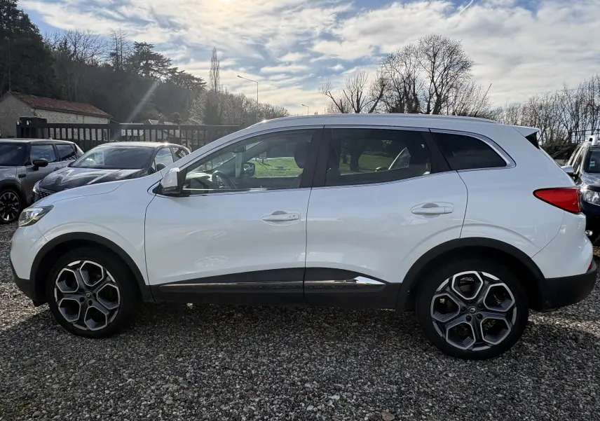Profil côté gauche d'un Renault Kadjar blanc 2015 avec jantes alliage et détails noirs sur les bas de caisse.