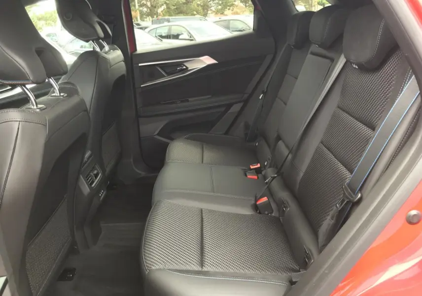 Vue intérieure côté droit des sièges arrière en cuir noir avec surpiqûres bleues du Renault Austral Esprit Alpine rouge et noir.