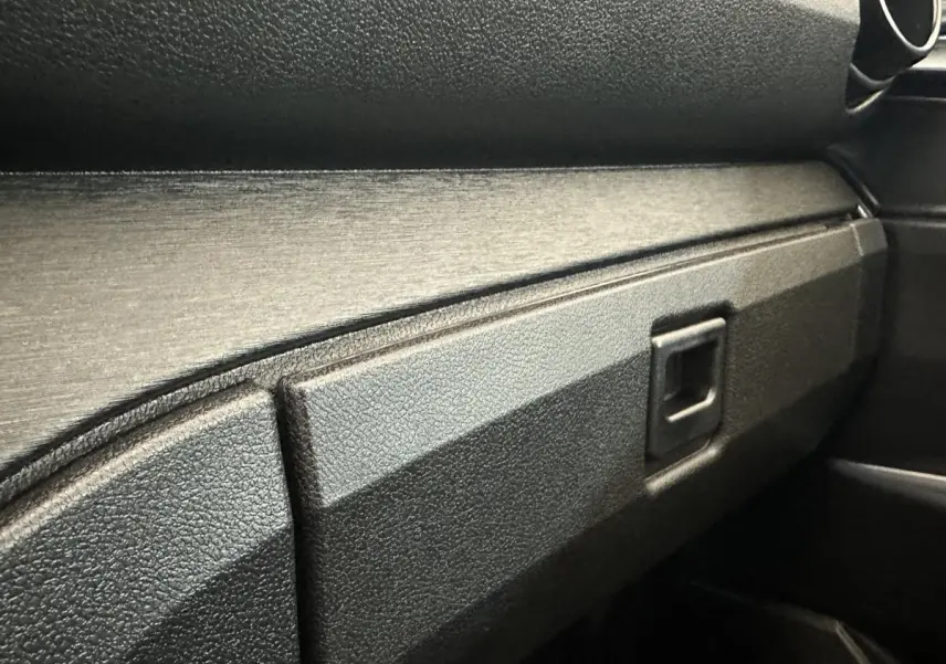 Détail de la boîte à gants noire côté passager de l'AIXAM Ambition E City Pack 2026, intérieur sobre et texturé.