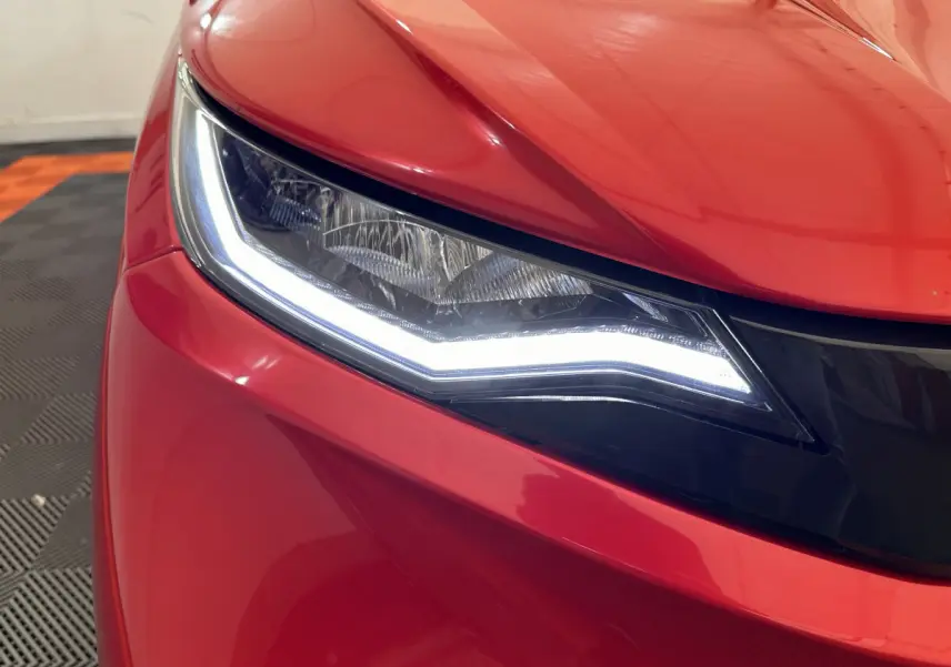 Gros plan sur le phare avant gauche d'une Aixam Ambition E City Pack rouge 2026 avec éclairage LED distinctif.