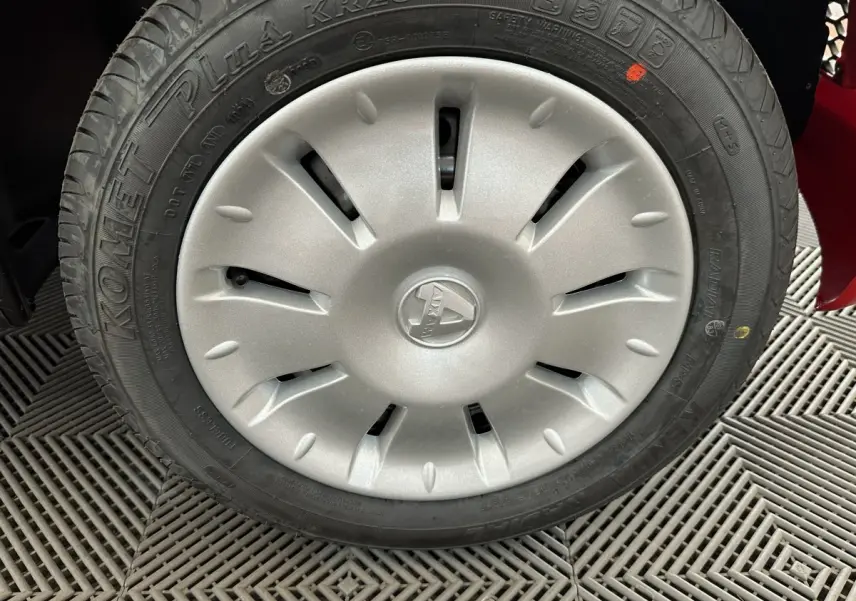 Gros plan sur la roue avant droite d'une Aixam Ambition E City Pack rouge avec enjoliveur argenté et logo central.