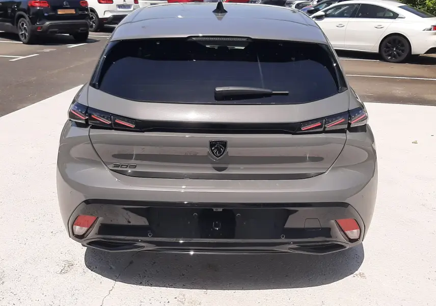 Vue arrière d’une Peugeot 308 III Ph.2 gris selenium avec feux LED et logo lion central sur parking.