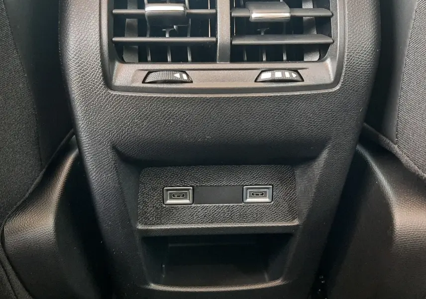 Vue rapprochée de la console arrière noire de la Peugeot 308 III Ph.2 avec bouches d'aération et deux ports USB-C.