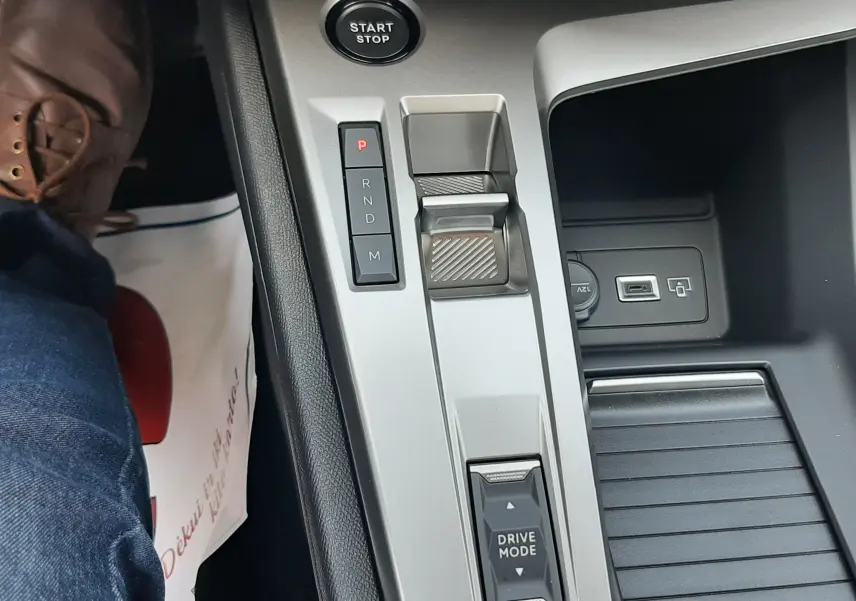Gros plan sur la console centrale grise du Peugeot 308 III Ph.2 avec sélecteur de boîte auto, bouton start/stop et commande Drive Mode.