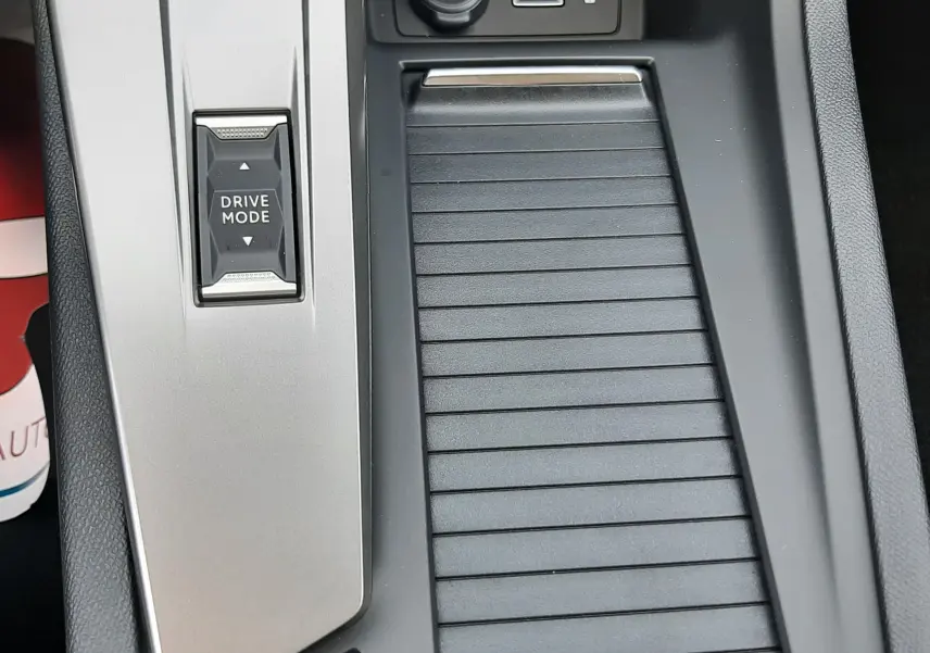 Gros plan sur la console centrale grise de la Peugeot 308 III Ph.2 avec bouton Drive Mode et prises USB et 12V.
