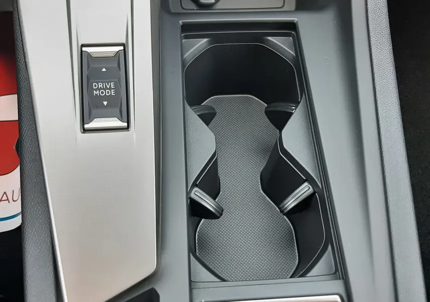 Vue en plongée du porte-gobelets central et du bouton Drive Mode de la console intérieure grise du Peugeot 308 III Ph.2.
