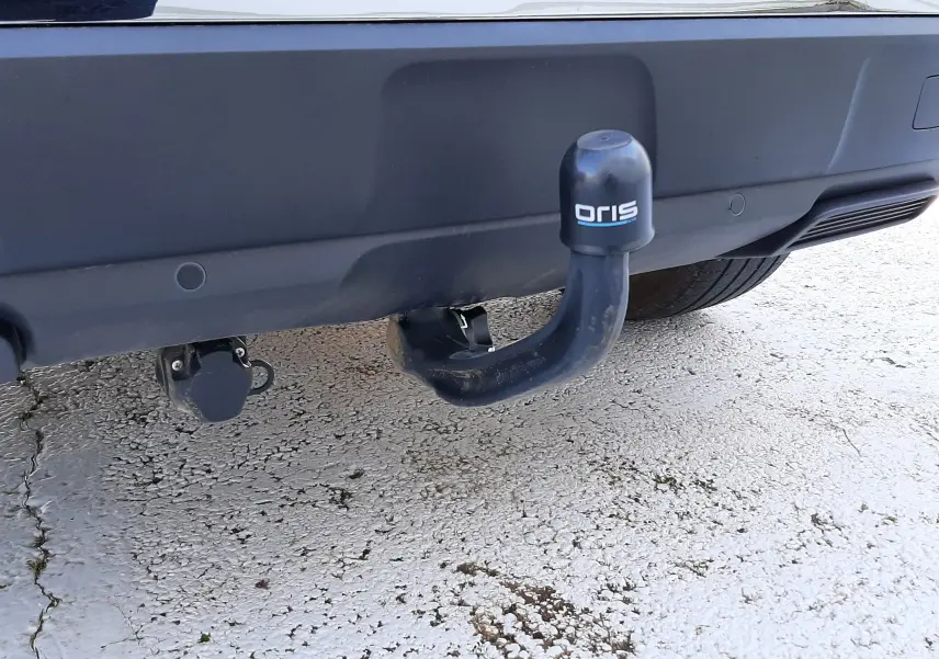 Gros plan sur l'attelage de remorque noir fixé au pare-chocs arrière gris platinium d'un Peugeot 3008 2023.