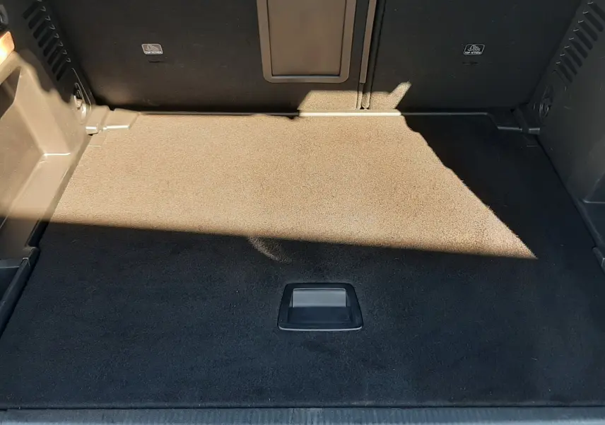 Coffre spacieux vu de face du Peugeot 3008 gris platinium, avec tapis de sol noir et ouverture centrale.