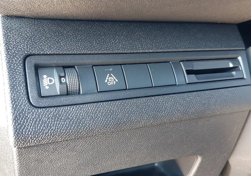 Détail intérieur montrant les commandes de réglage des phares et d'aide à la conduite sur un Peugeot 3008 gris platinium.