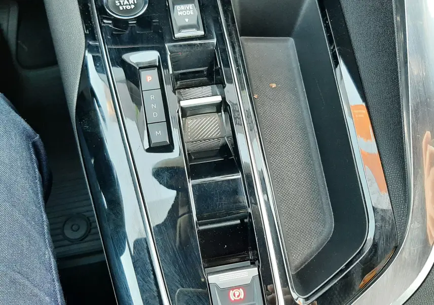 Vue rapprochée de la console centrale noire brillante du Peugeot 3008 2023 avec sélecteur de boîte auto et bouton start/stop.