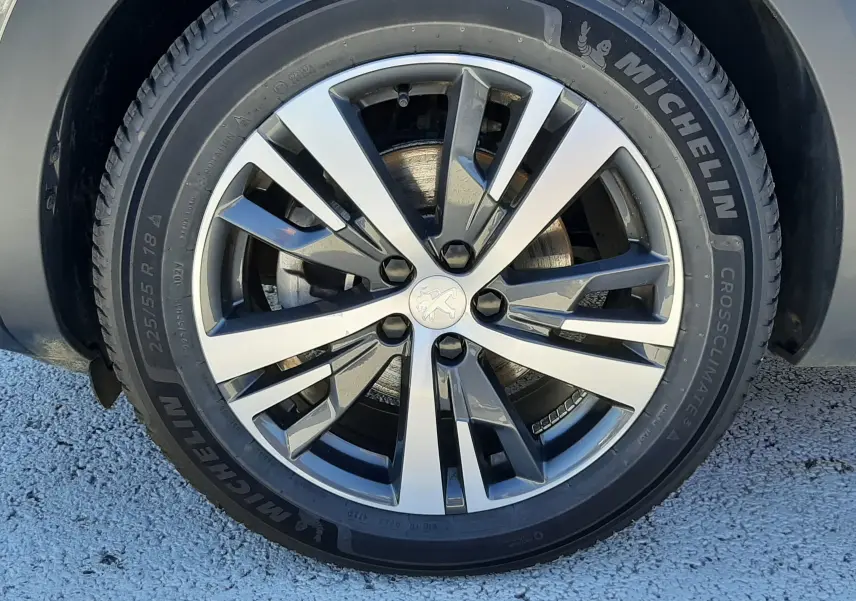 Gros plan sur la roue avant droite d’un Peugeot 3008 gris platinium, jante alliage bicolore et pneu Michelin.
