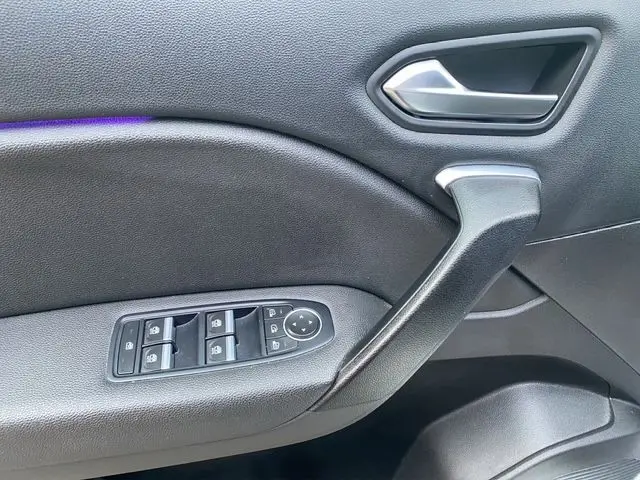 Gros plan sur la porte intérieure côté gauche du Renault Captur blanc nacré, avec commandes des vitres et poignée noire.