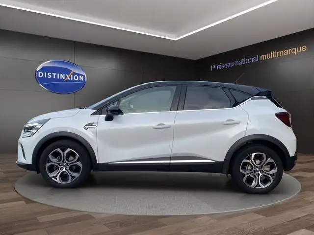 Profil droit du Renault Captur blanc nacré avec toit noir, jantes alliage 18 pouces et détails noirs contrastants.
