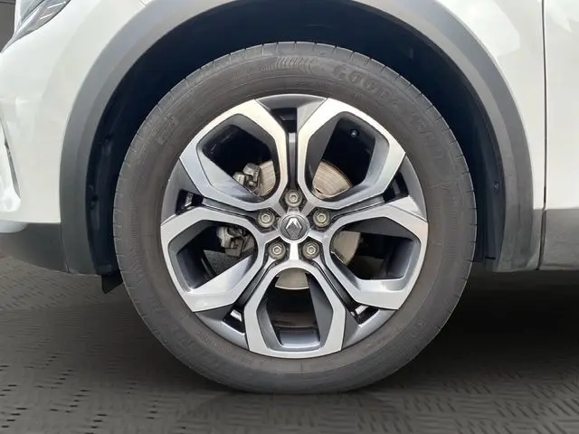 Gros plan sur la roue avant gauche d'un Renault Captur blanc nacré avec toit noir, montrant le passage de roue et le pneu.