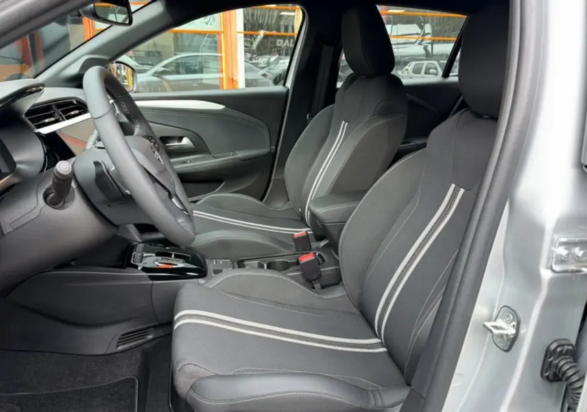 Vue intérieure côté conducteur de l’Opel Corsa gris kristall, sièges tissu avec bandes blanches et volant multifonctions.