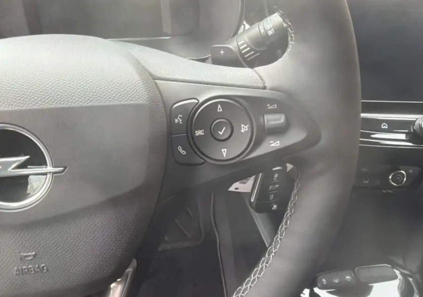 Gros plan sur le volant cuir multifonctions de l’Opel Corsa Hybrid 2026, avec commandes intégrées et tableau de bord noir.