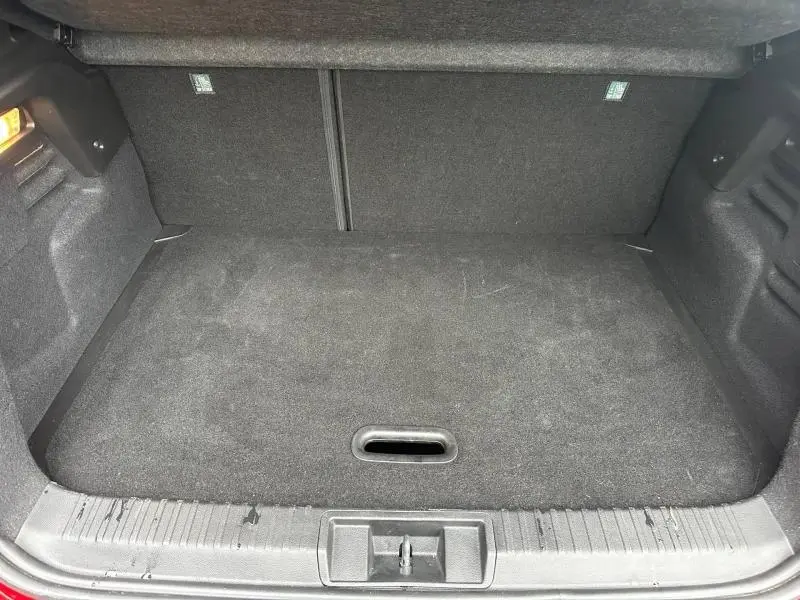 Coffre ouvert vu de l'arrière d'un Renault Captur 2025 Rouge Flamme/Noir Étoilé, espace de chargement vide et tapis noir.